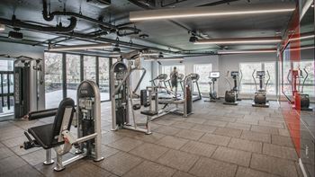 A gym with a variety of equipment including a rowing machine, a treadmill, and a weight bench.at Axle, Seattle, 98119