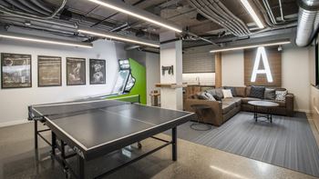 A ping pong table is in the middle of a room with a couch and a coffee table.at Axle, Seattle