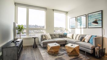 A living room with a grey couch, a wooden coffee table, and a large window.at Axle, Seattle Washington