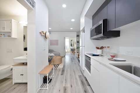 A modern kitchen with white cabinets and a wooden floor.