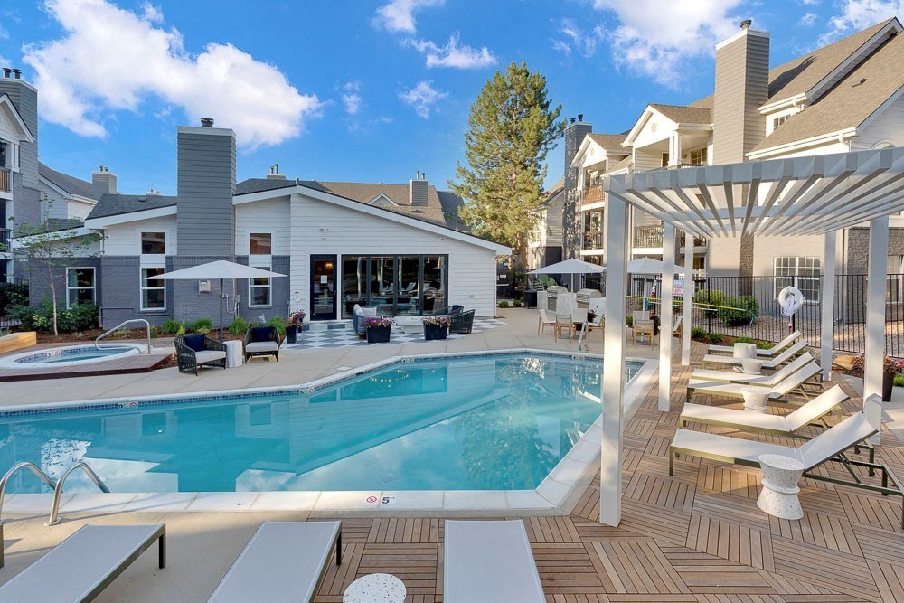 A large outdoor swimming pool with sun loungers and a pergola.