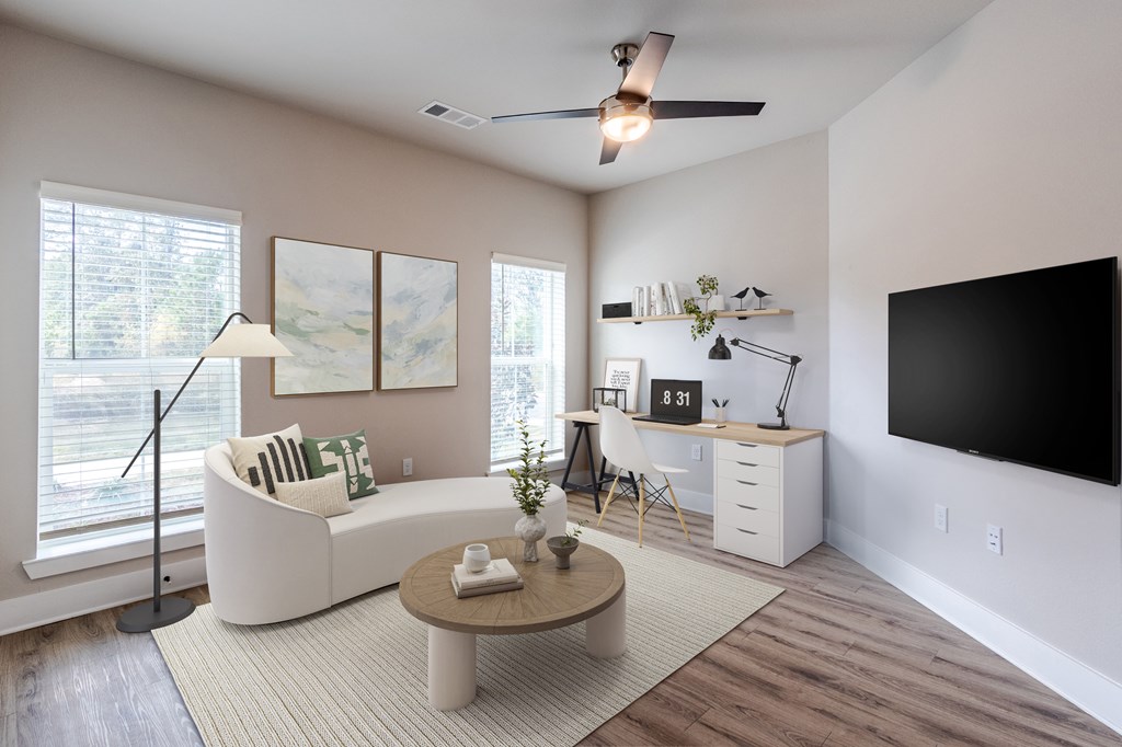 A living room with a white couch, a brown coffee table, and a flat screen TV mounted on the wall.