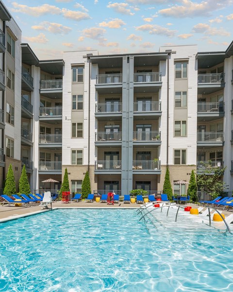 A large swimming pool in front of a multi-story apartment building.