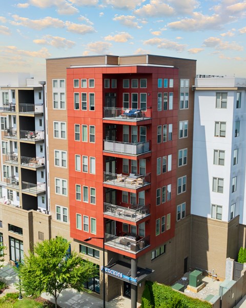 A tall apartment building with a red and beige facade.