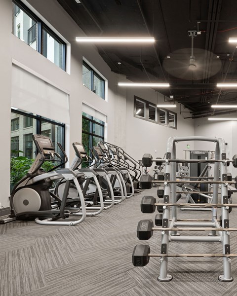 A gym with a variety of equipment including treadmills, weights, and exercise machines.