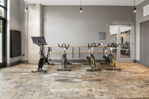 A room with a tiled floor and a row of stationary bikes.