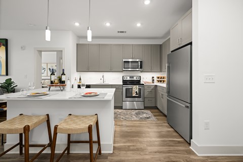 A modern kitchen with a white island and wooden bar stools.