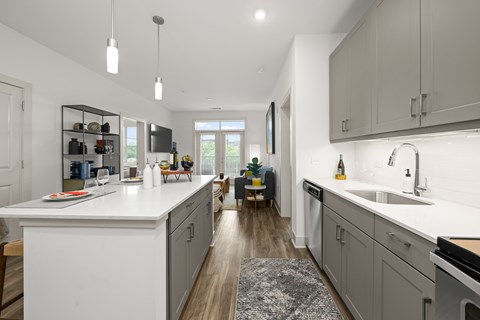 A modern kitchen with white countertops and wooden floors.
