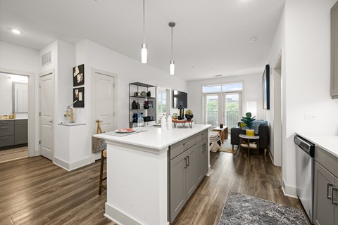 A modern kitchen with white cabinets and a wooden floor.