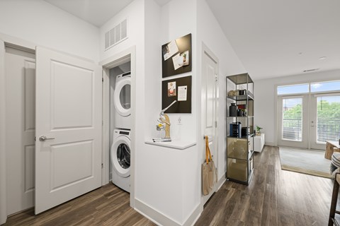 A laundry room with a washer and dryer, a small pantry, and a sliding glass door leading to a balcony.
