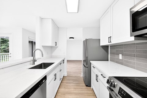 A kitchen with white cabinets and a black refrigerator.