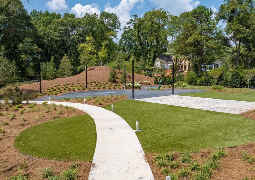a walkway through a park with grass and trees