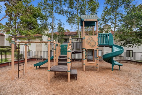A playground with a green slide and a wooden structure.