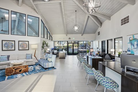 A modern living room with a long white couch and a blue patterned chair.