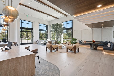 A large, modern living room with a curved wooden table and a variety of seating options.
