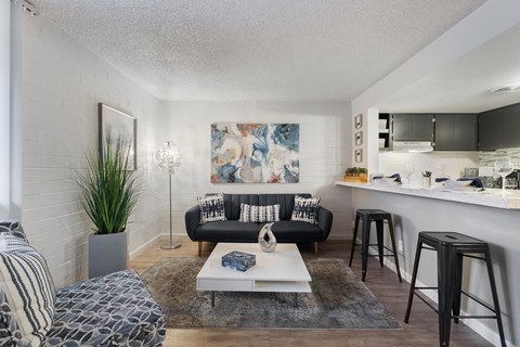 A living room with a black couch, a white coffee table, and a painting on the wall.