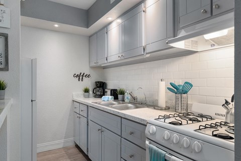 A modern kitchen with a white stove and grey cabinets.