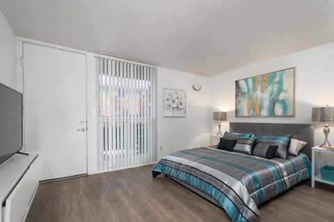 A bedroom with a bed, nightstand, and a painting on the wall.