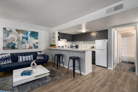A modern kitchen with a white refrigerator and a bar area with stools.