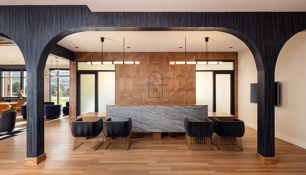 A modern room with a large bed and black chairs.