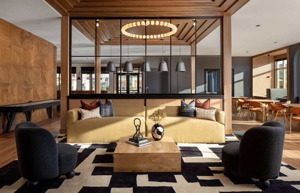 A modern living room with a yellow sofa and a black and white rug.