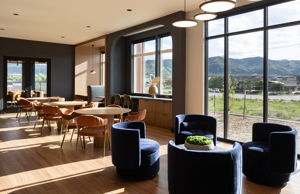 A room with a table and chairs with a view of the mountains outside the window.
