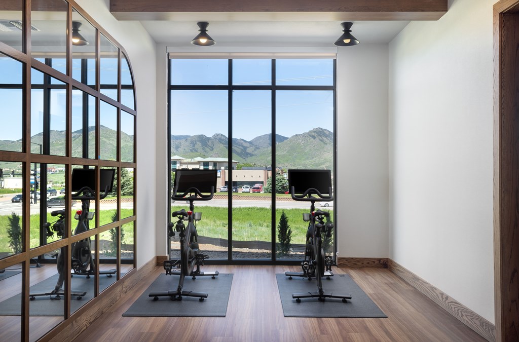 A room with exercise bikes and a view of the mountains outside the window.