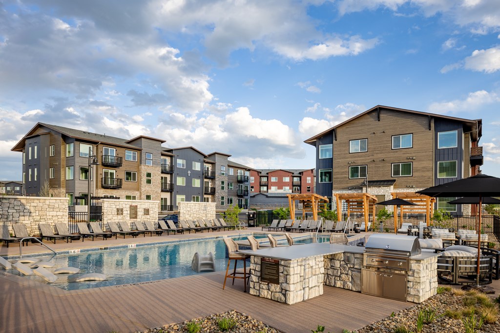 A large outdoor swimming pool surrounded by a wooden deck and lounge chairs.
