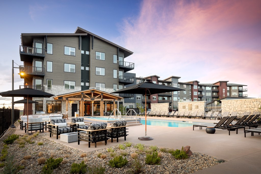 A modern apartment complex with a pool and lounge area.