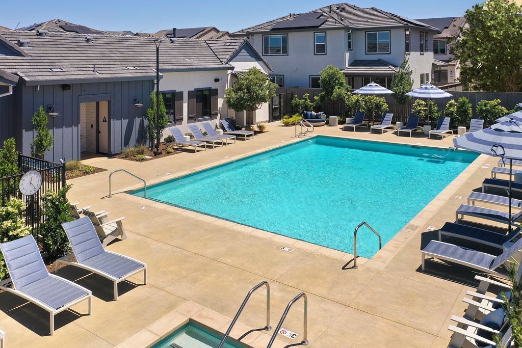 A swimming pool surrounded by lounge chairs and umbrellas.