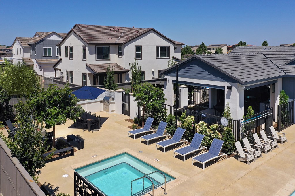 A pool surrounded by lounge chairs and a building in the background.