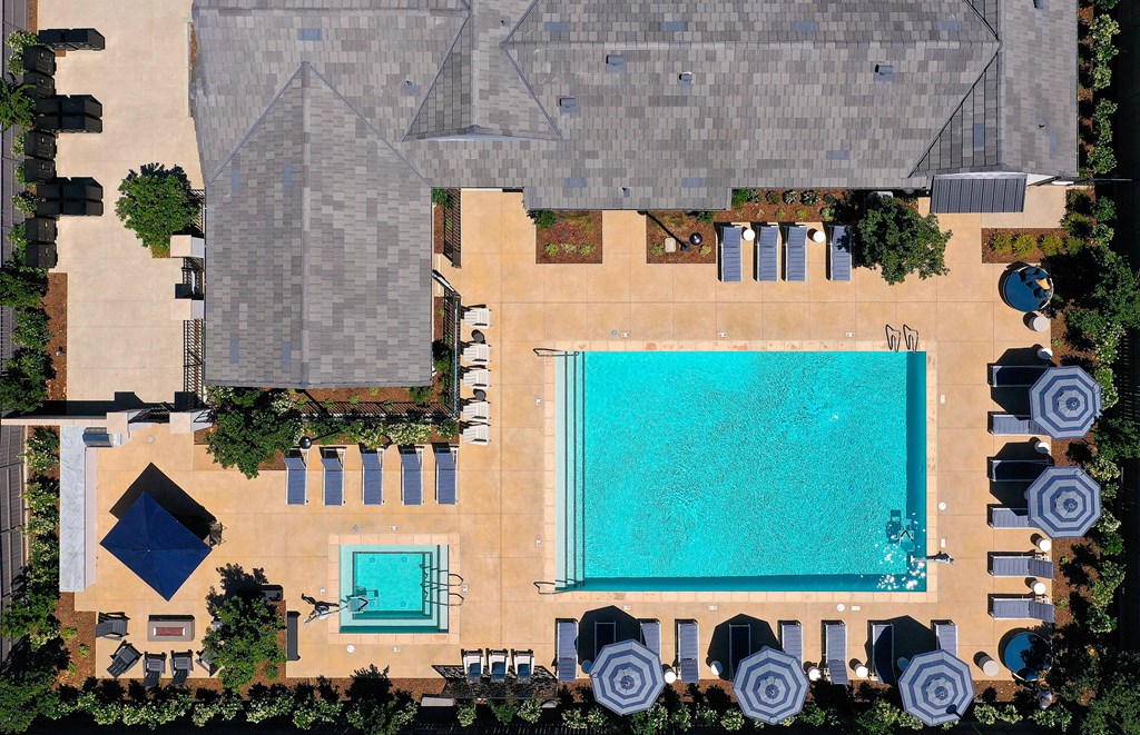 An aerial view of a pool surrounded by lounge chairs and umbrellas.