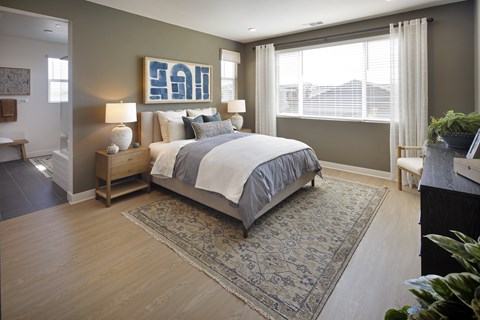 A bedroom with a large bed and a rug on the floor.