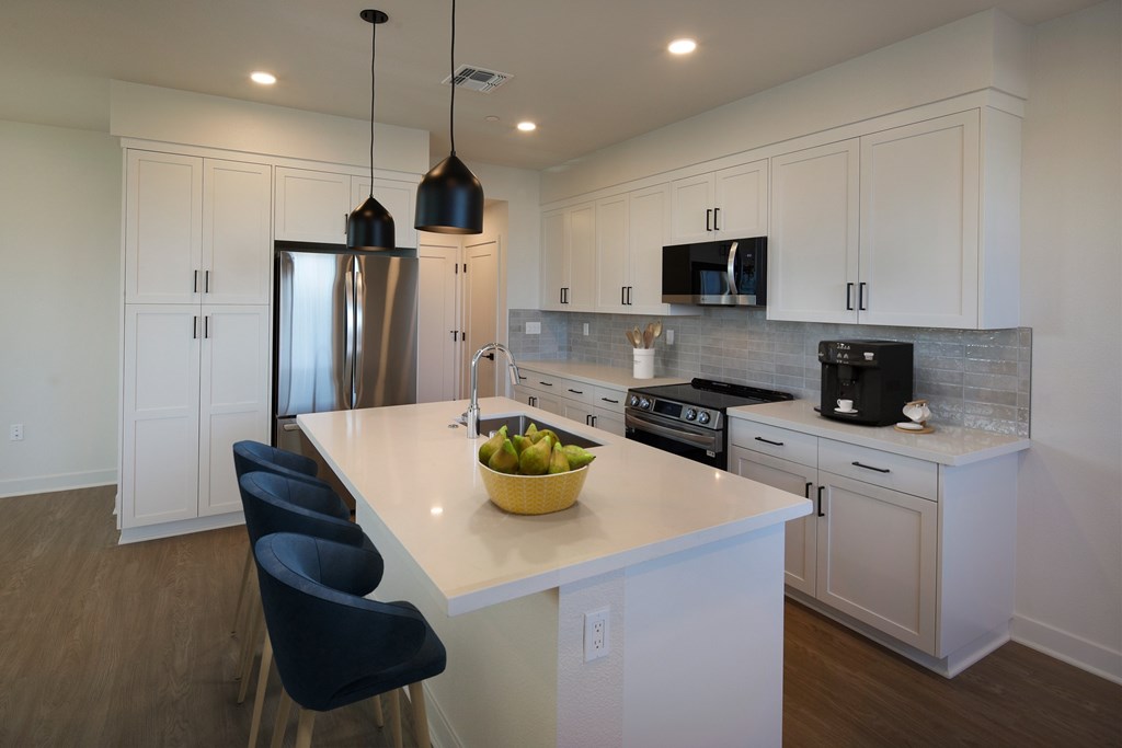 A kitchen with a white counter top and black chairs.