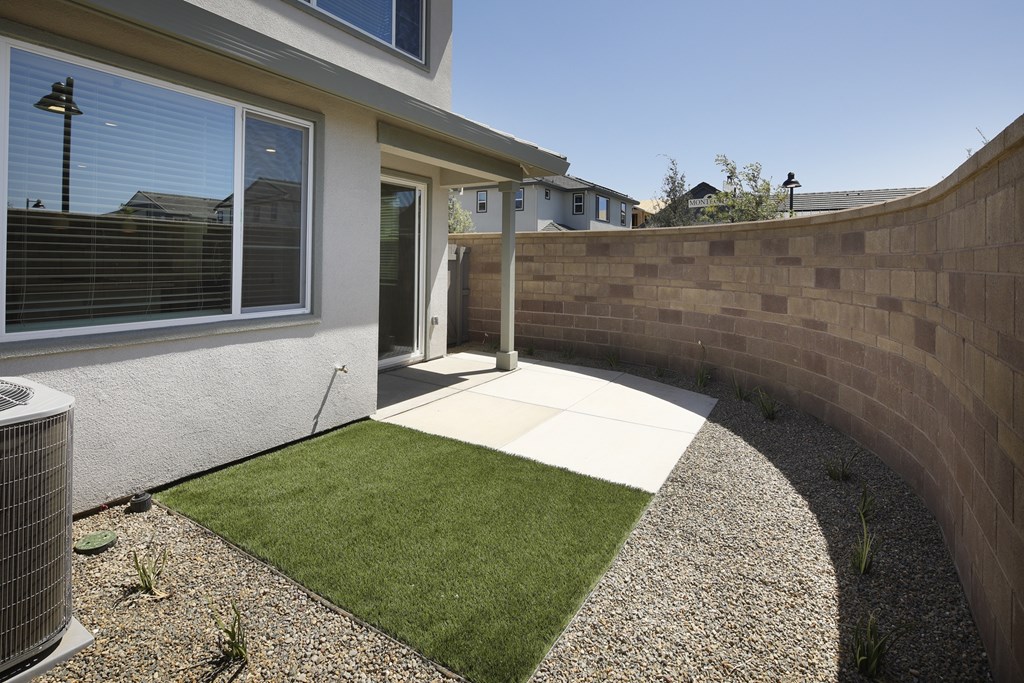 A house with a grey wall and a green lawn.