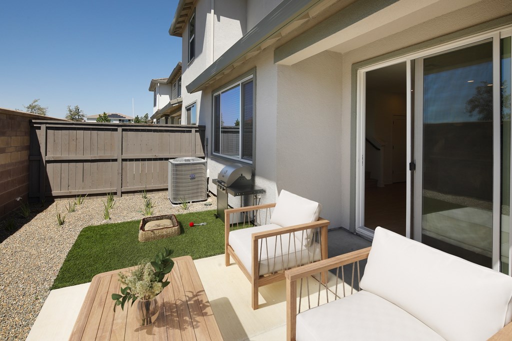A patio with a white couch and a wooden table.