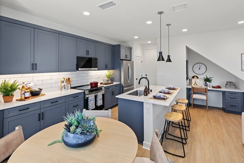A kitchen with a table and chairs in the foreground and a staircase in the background.
