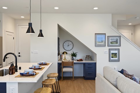 A modern kitchen with a bar stool and a dining table with chairs.