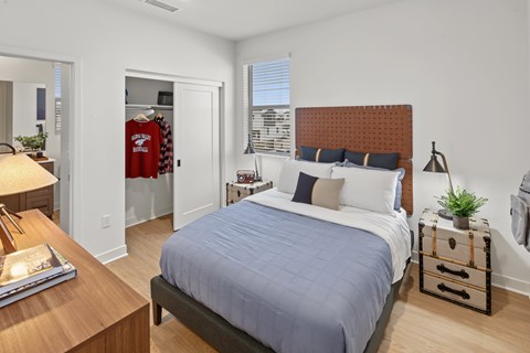 A bedroom with a bed, nightstand, and a window with blinds.