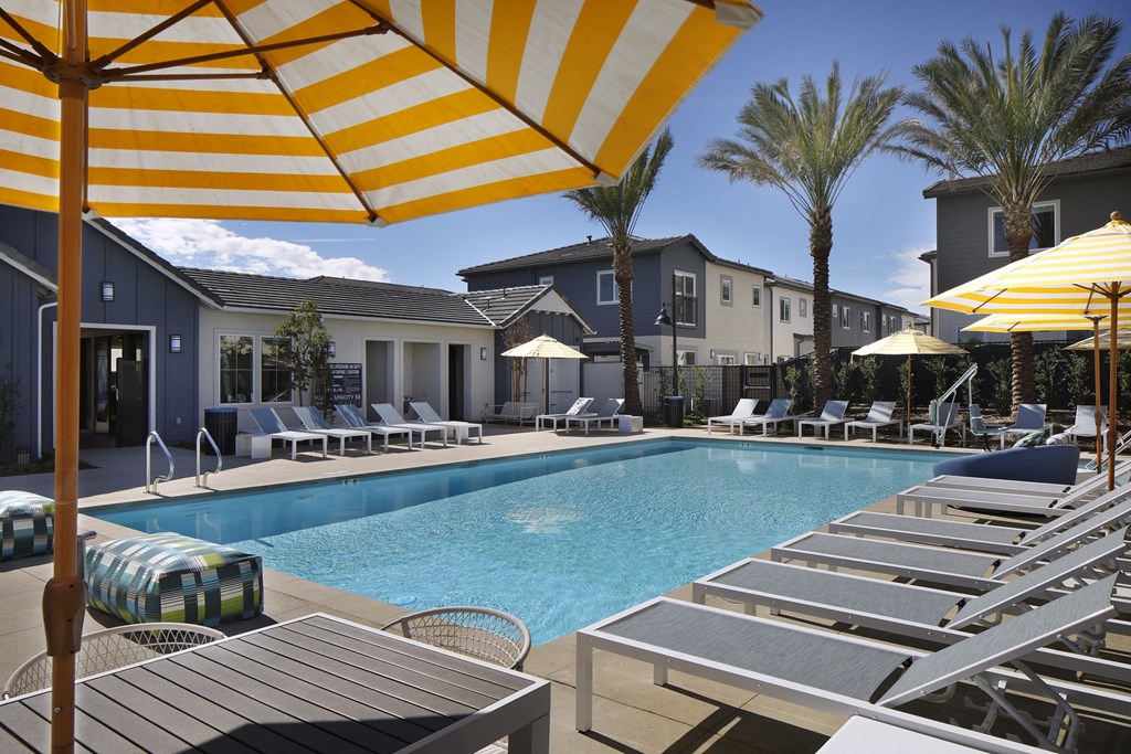A pool with sun loungers and umbrellas.
