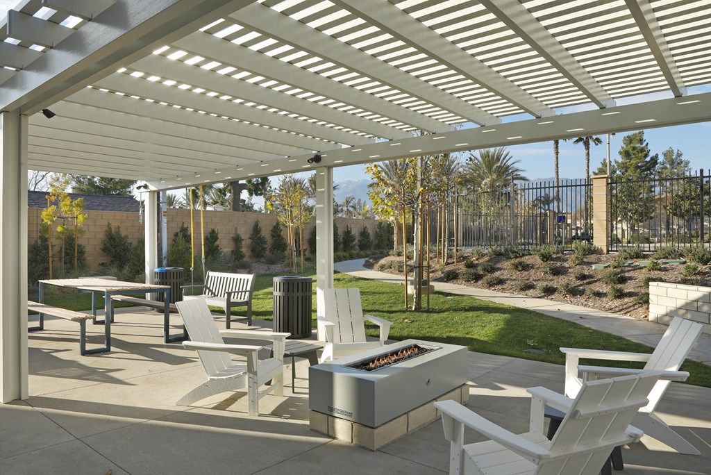 A patio with white chairs and a grill under a white awning.