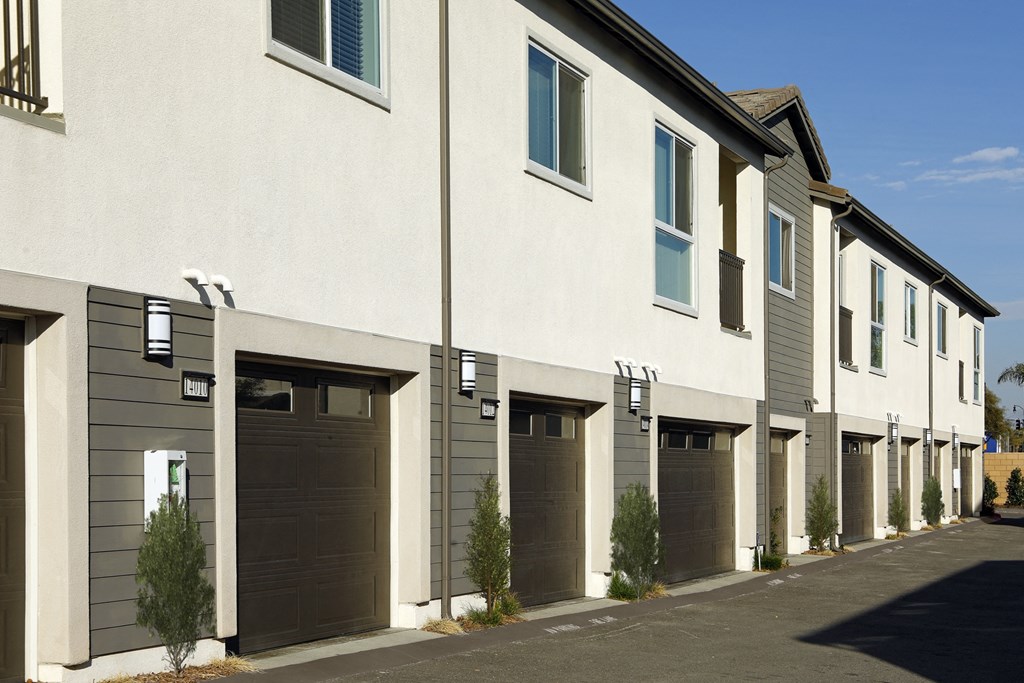 A row of houses with garages and trees in front.