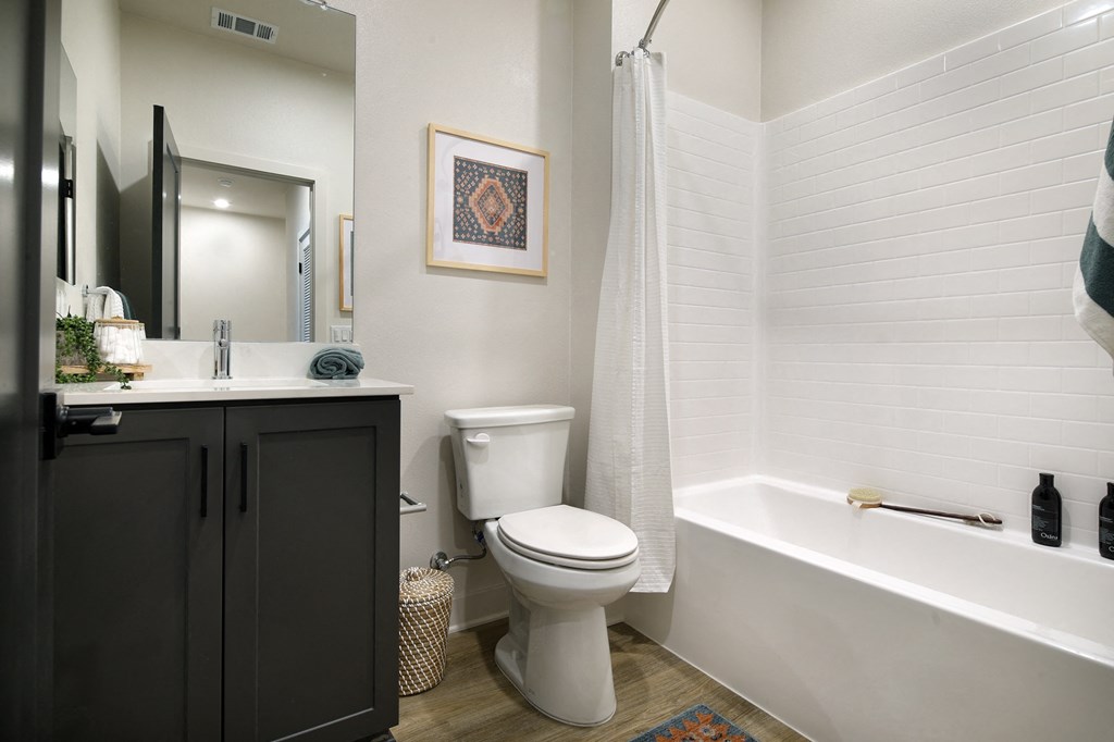 A white toilet sits in a bathroom next to a white bathtub.