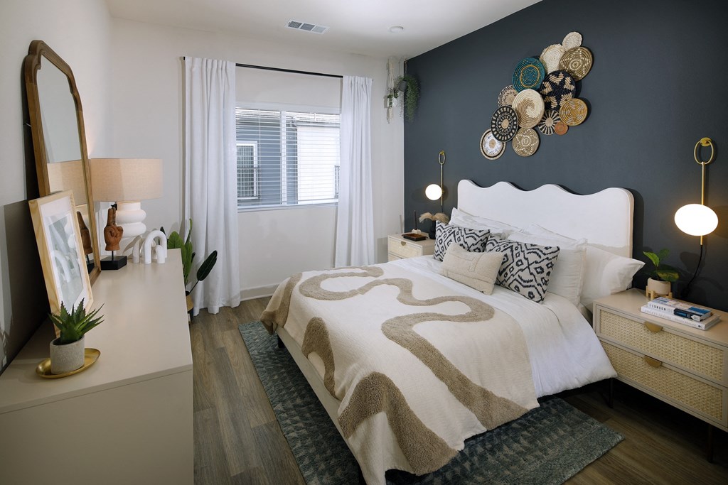 A bedroom with a large bed and a mirror on the dresser.