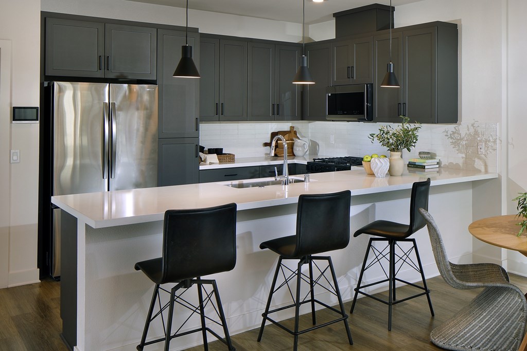 A kitchen with a white island and black chairs.