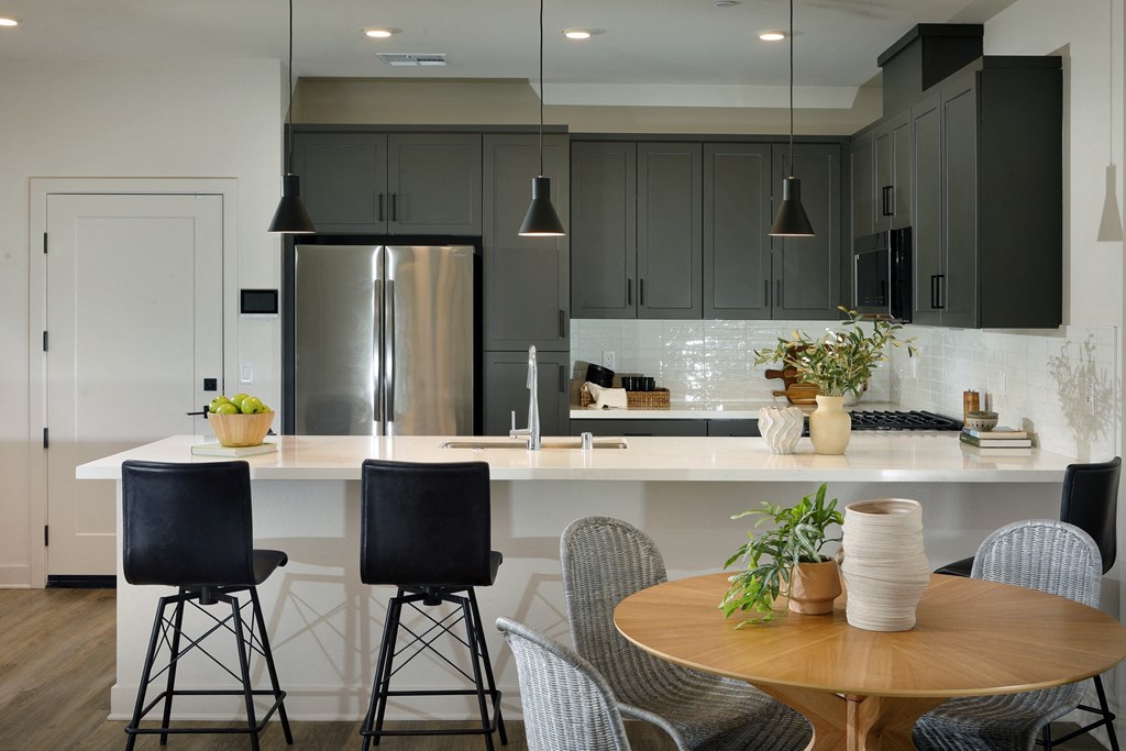A modern kitchen with a wooden table and black chairs.