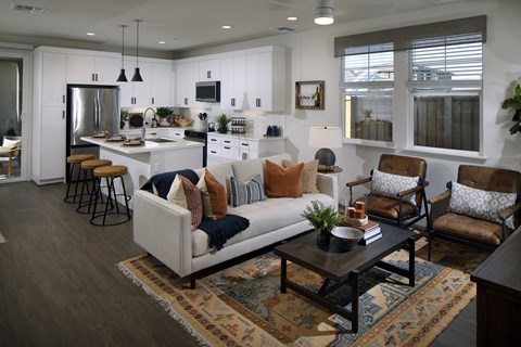 A modern living room with a white couch and a kitchen in the background.