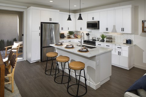 A kitchen with white cabinets and a large island with bar stools.