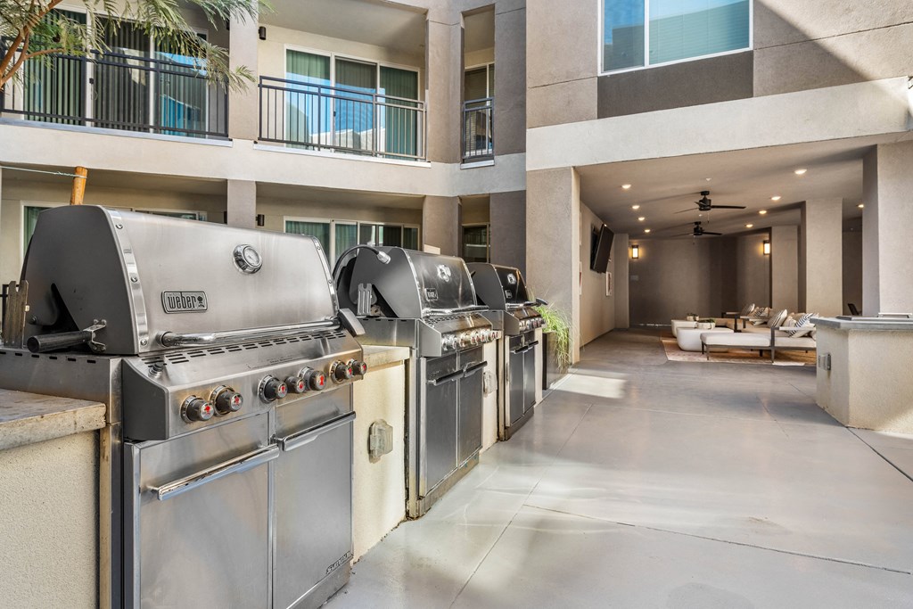 A row of outdoor grills are lined up on a patio.
