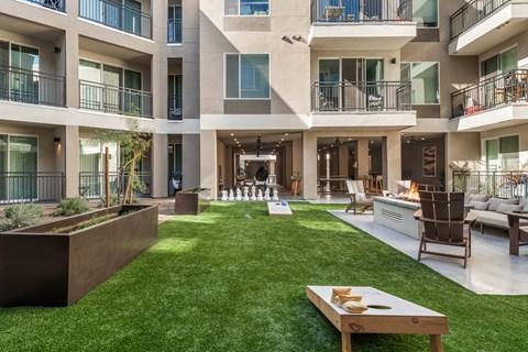 A modern courtyard with a wooden bench and a fireplace.